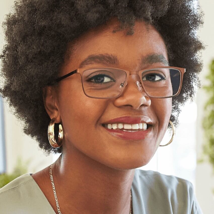 Person wearing rectangular eyeglasses with brown frames and gold hoop earrings, smiling.