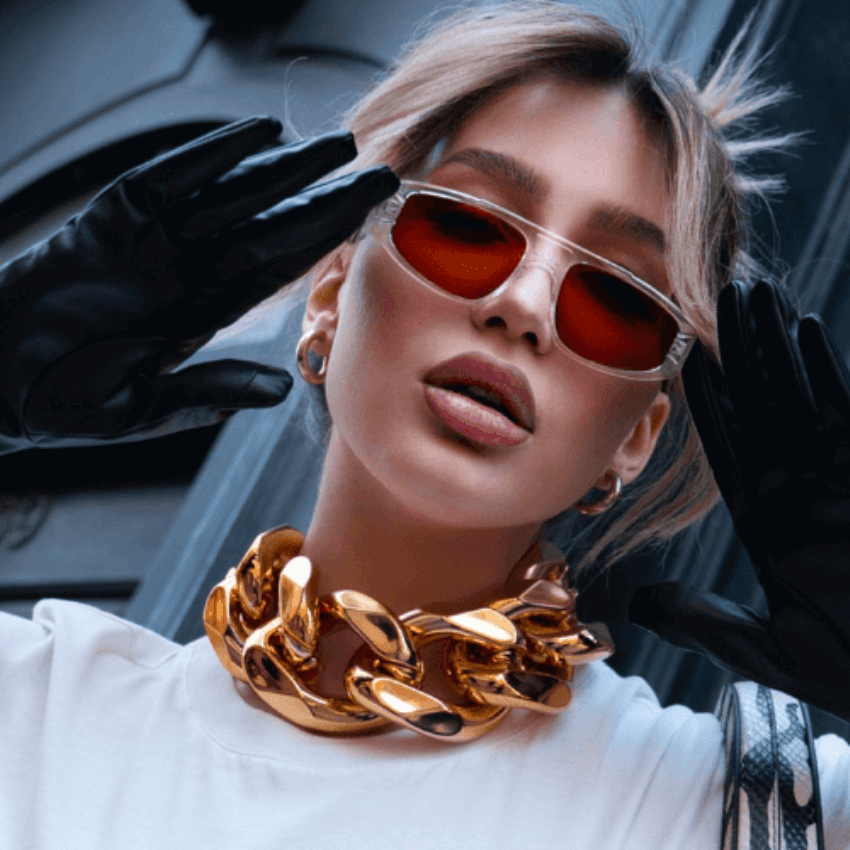 Bold gold chain necklace, red sunglasses, and black gloves worn with a white T-shirt.