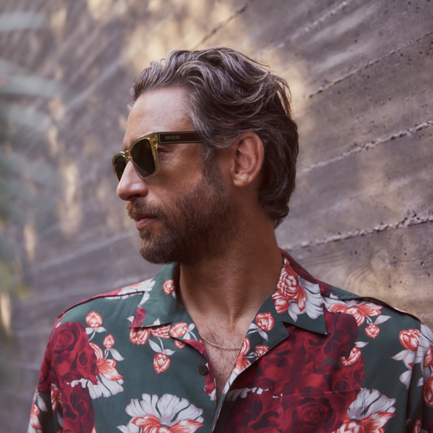 Man wearing Vysen Eyewear sunglasses and a green floral shirt with red and white flowers.