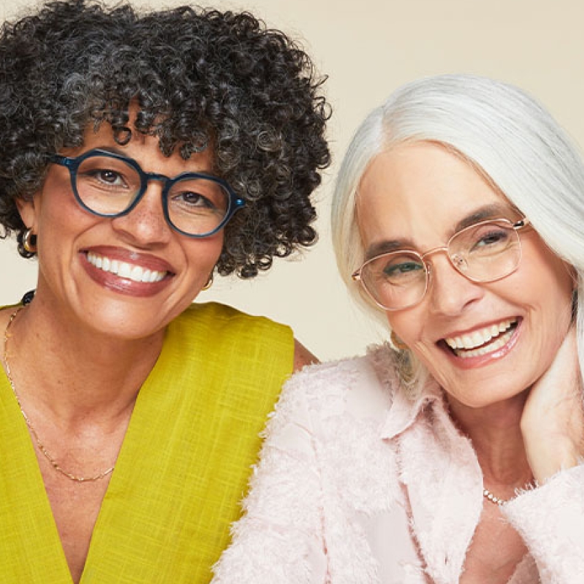 Two smiling individuals wearing stylish eyeglasses; one with dark frames and the other with light frames.
