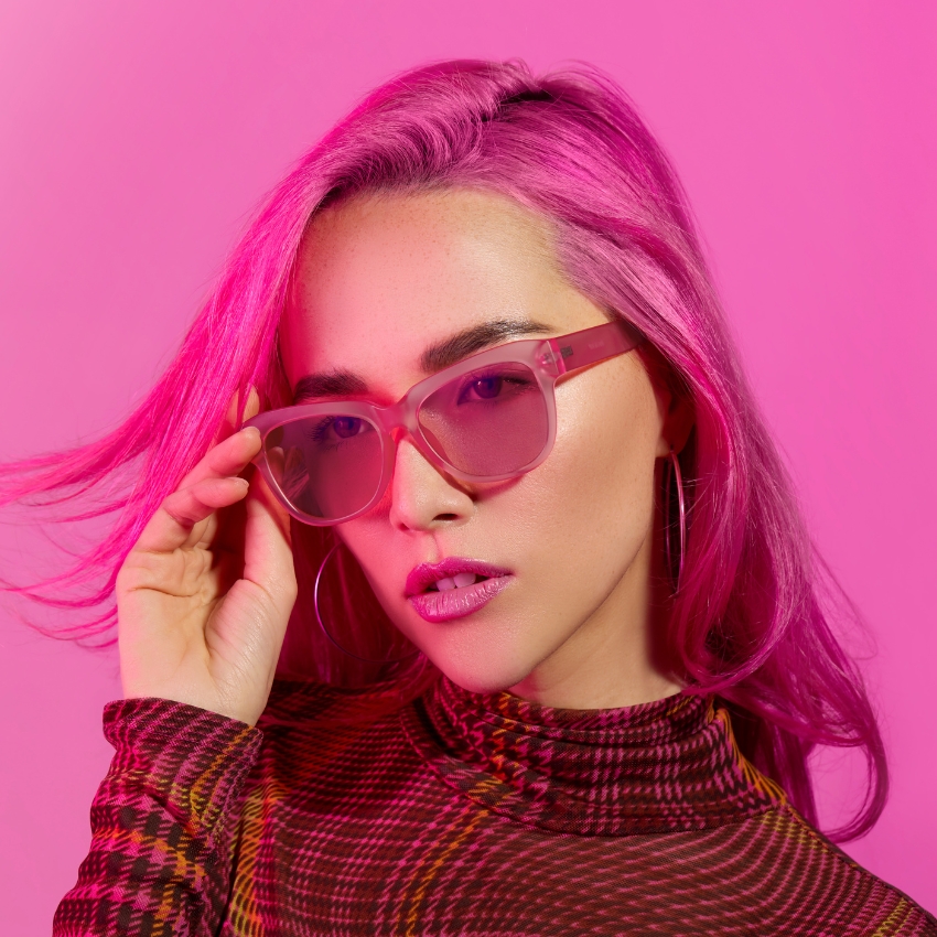 Pink translucent sunglasses worn by a person with vibrant pink hair.