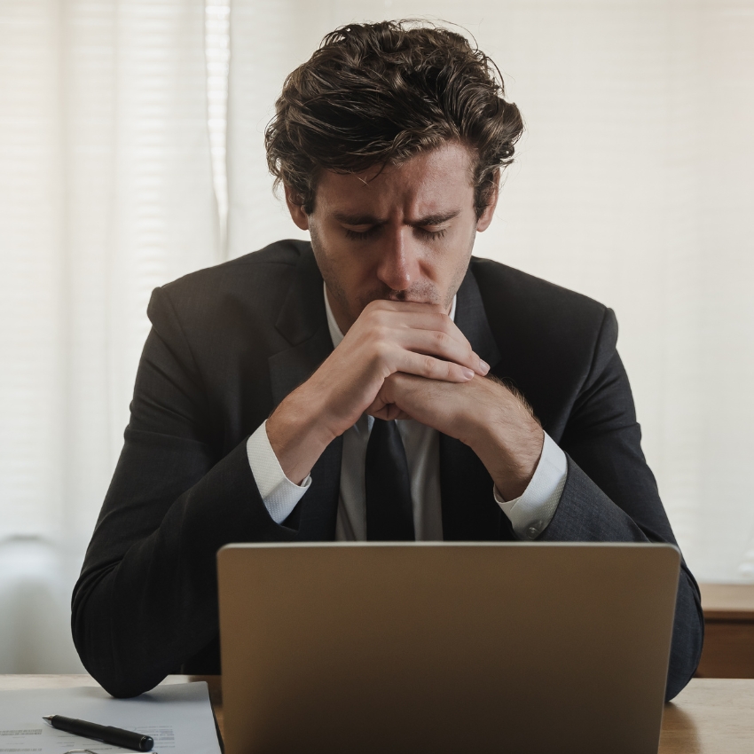 Man in a suit concentrating while working on a laptop.